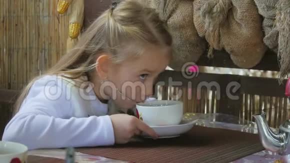 可爱的小女孩在咖啡馆喝茶清淡的早餐小白种人女孩在咖啡馆喝茶视频的预览图
