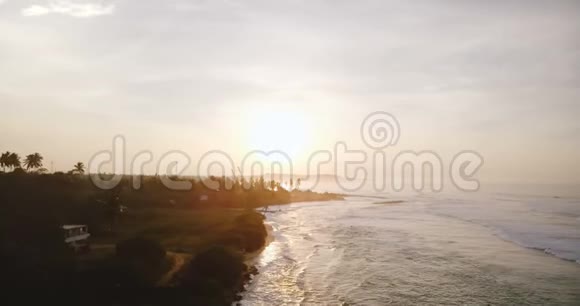 无人机沿着令人叹为观止的热带日落海滩向前飞行白色泡沫的海浪在惊人的海岸线上破碎视频的预览图