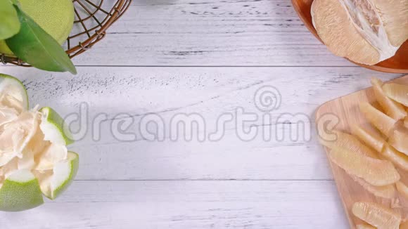 年轻的亚洲妇女正在准备和供应剥皮的新鲜蜜柚在厨房的托盘上明亮的白色木桌顶部的景色超过了视频的预览图