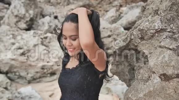 印度尼西亚女孩在巴厘岛美丽的岩石海滩上摆姿势伊多尼西亚视频的预览图