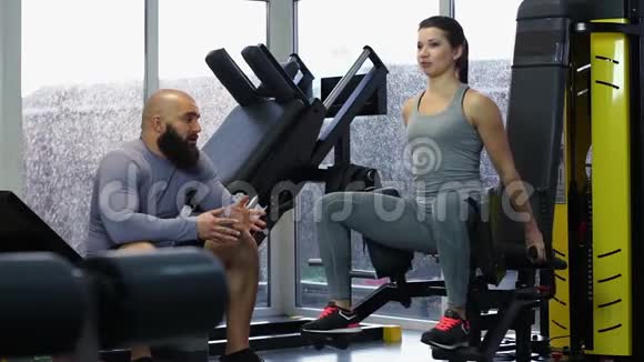 积极的年轻女子在健身房训练与英俊的运动男子交谈击掌视频的预览图