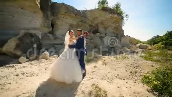 新娘和英俊的新郎走在沙岩附近视频的预览图