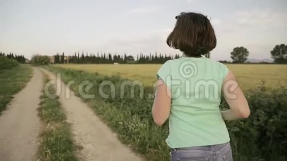 年轻的白种人妇女在西班牙农村公路上通过农村麦田享受生活和跑步视频的预览图