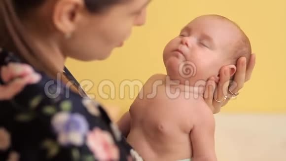 年轻的母亲正在摇着婴儿的手臂亲吻他视频的预览图