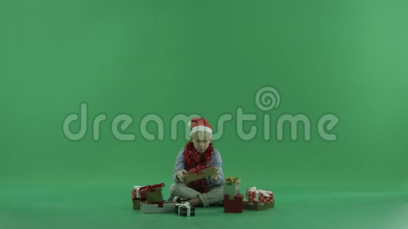小男孩坐在圣诞礼物中看着它们绿色的彩色钥匙背景视频的预览图