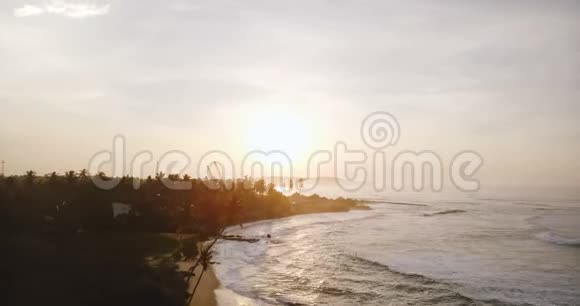 无人机在美丽的日落海滩上空飞行白色的海浪到达海岸线与正在进行的建筑工地视频的预览图