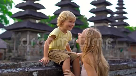 一名年轻女子和她的儿子在巴厘岛的塔曼阿云寺周围行走时被慢镜头拍到视频的预览图
