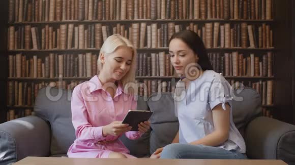 两个幸福的女人在咖啡馆里读电子书视频的预览图