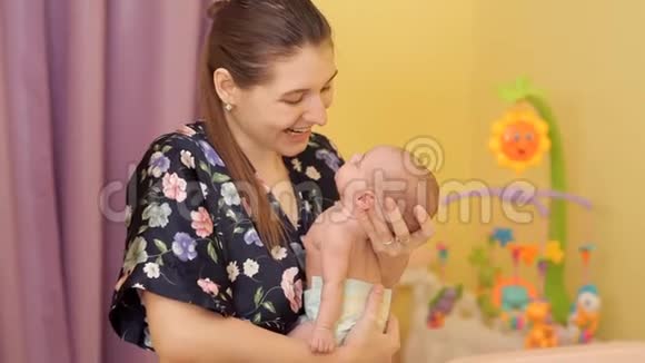 年轻的母亲正在摇着婴儿的手臂亲吻他视频的预览图