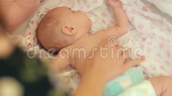 妈妈在婴儿的竞技场上触摸卧铺婴儿在母亲的抚摸下扭动身体视频的预览图