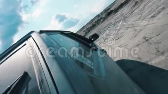 从黑色俄罗斯汽车侧面近景在沙质的地面上在蓝色多云的天空下行驶录像赛马比赛视频的预览图