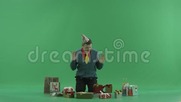成年人带着生日礼物坐着试着选择一个打开绿色的关键背景视频的预览图