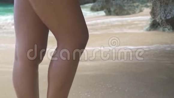 美丽的女人穿比基尼在岩石海滩和海浪背景上摆姿势穿着热带泳衣的漂亮女人视频的预览图