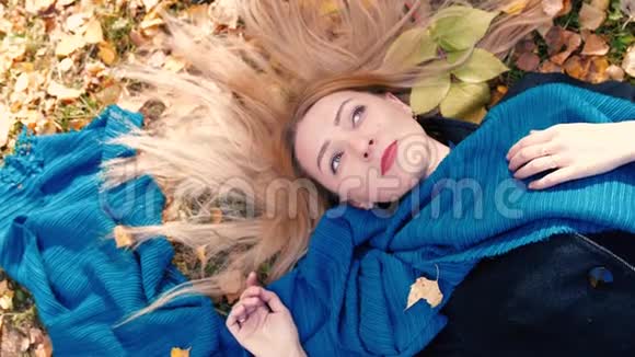俯瞰秋日金发美女躺在树叶上慢动作3840x2160视频的预览图