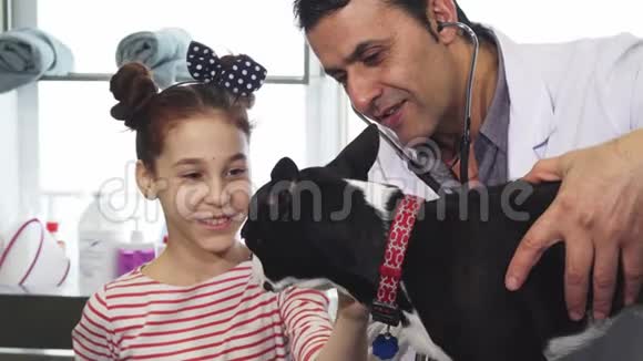 可爱的小女孩在兽医克莱尼格的体检中抚摸她的狗视频的预览图