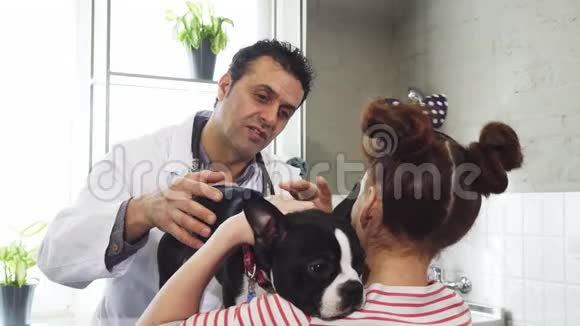 成熟的职业兽医在抚摸她的狗时和小女孩说话视频的预览图