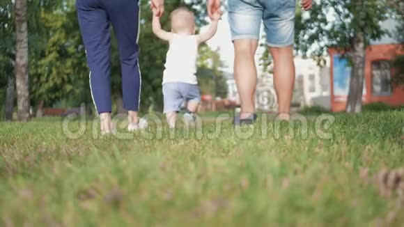 爸爸和妈妈和儿子牵着手在公园里家人在公园散步视频的预览图