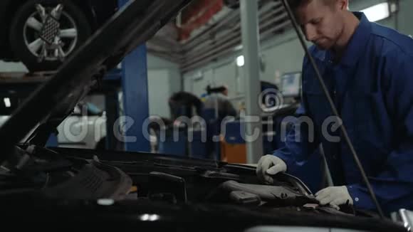 一名汽车修理工在汽车车间检查机油油位男子肖像发动机汽车修理服务视频的预览图