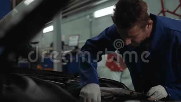 一名汽车修理工在汽车车间检查机油油位男子肖像发动机汽车修理服务视频的预览图