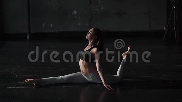 苗条的女孩独自做瑜伽年轻的女人坐在绳子上做伸展运动慢动作视频的预览图