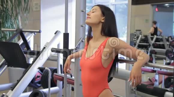 漂亮的女人在健身房里摆着紧身运动套装模拟器视频的预览图