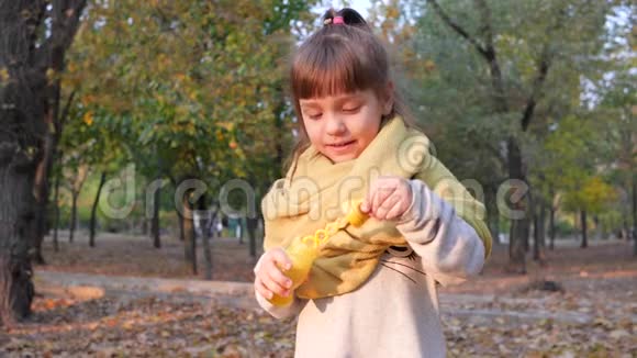 一个可爱的孩子在秋天公园吹肥皂泡和微笑的肖像视频的预览图