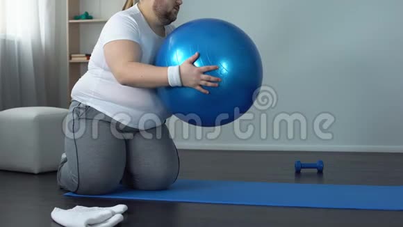 疲惫的没有动力的肥胖男人躺在健身球上减肥健身计划视频的预览图