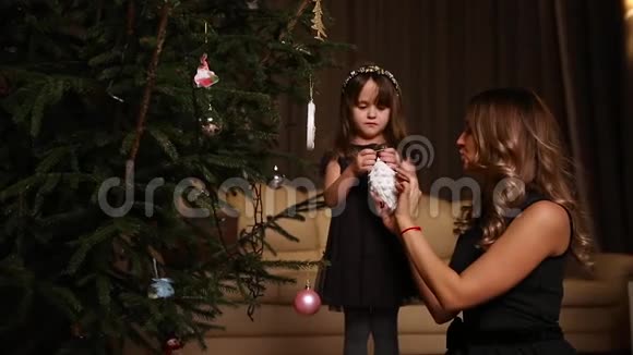 妈妈给女儿一个圣诞玩具所以她挂在树上视频的预览图