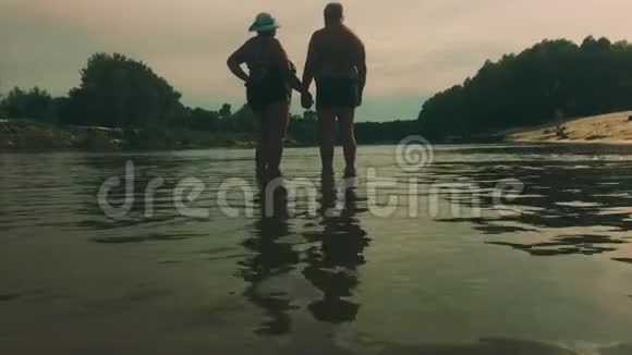 成熟的夫妻拥抱俯瞰河流一对漂亮的老人在水边快乐老人牵着手视频的预览图