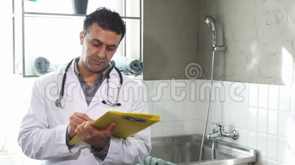 成熟的男性兽医对着镜头微笑地填写医疗文件视频的预览图