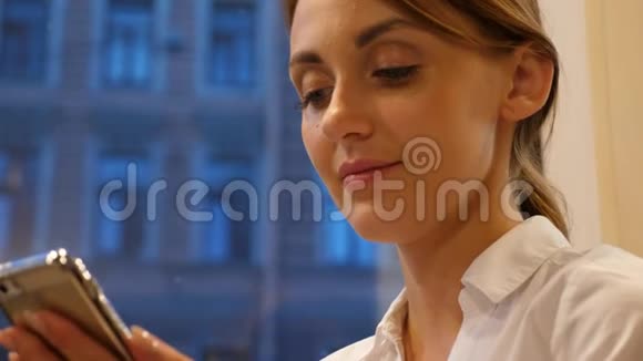 坐在靠窗的智能手机女人的画像视频的预览图