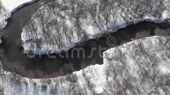 春天从河上的四架直升机上观看河水流淌在白雪和光秃秃的树木之间视频的预览图