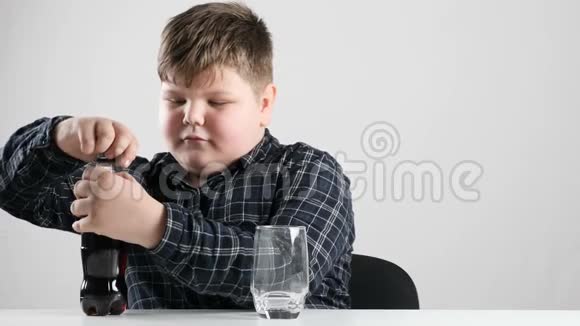 年轻的胖男孩把苏打水倒入玻璃杯中视频的预览图