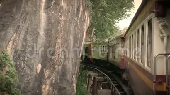 4K段的画面一列古老的火车在一条弯曲的尖轨上行驶弯上一座横跨葵河的桥电影彩色滤镜视频的预览图