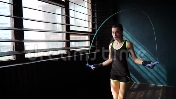 动作缓慢的年轻严肃的女拳击手裹着双手热身在健身房跳绳视频的预览图