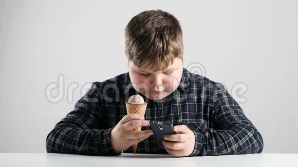 小胖男孩吃巧克力冰淇淋在智能手机上发短信50fps视频的预览图