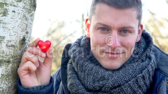 一个英俊的男人手里拿着一颗眨巴着眼睛的心视频的预览图