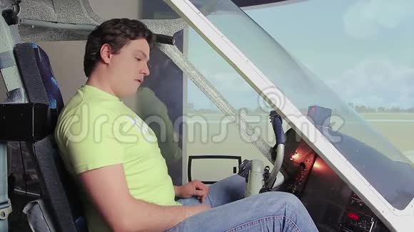 兴奋的年轻人坐在飞行模拟器里在驾驶舱甲板上转动控制装置视频的预览图