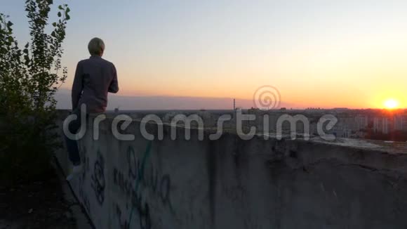 日落时分男人喝茶坐在大楼的顶部视频的预览图