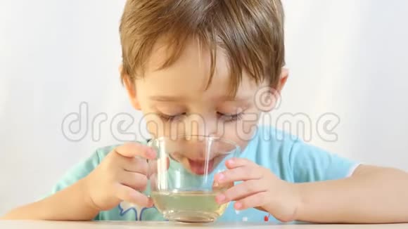一个快乐的孩子喝着杯子特写的茶视频的预览图