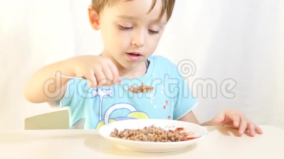 孩子吃荞麦粥配肉坐在桌边视频的预览图