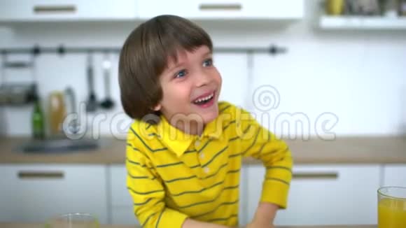 男孩笑了有魅力的父亲和非常可爱的儿子正在厨房的家里玩橙汁慢动作视频的预览图