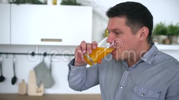 漂亮的年轻人在厨房里喝橙汁健康的生活方式慢动作视频的预览图