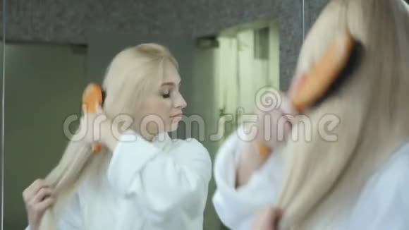 穿着浴袍的金发美女在镜子前梳头视频的预览图