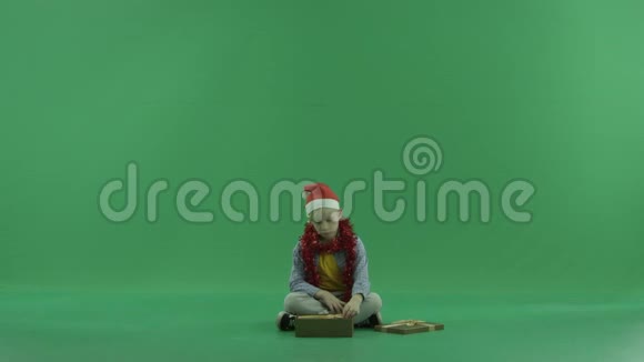 小悲伤男孩打开空的圣诞礼物绿色彩色钥匙背景视频的预览图