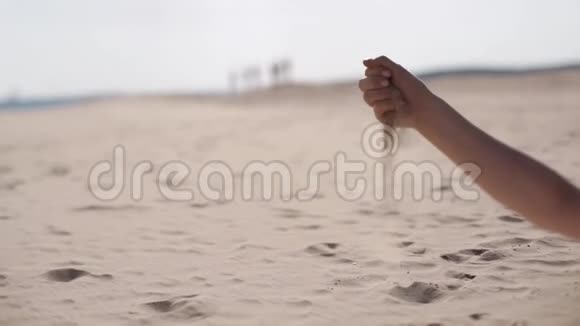 一个女孩正在用手指倒沙子女孩手沙子坐在沙滩上的女孩快乐的女孩视频的预览图