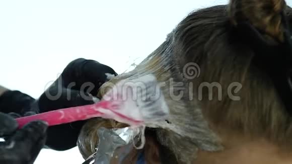 理发师为年轻女人做染发美丽发型和人的概念慢动作视频的预览图