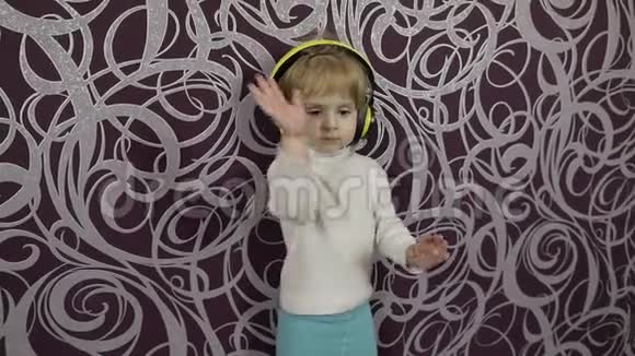 小快乐的孩子在沙发上跳舞在家听耳机里的音乐视频的预览图