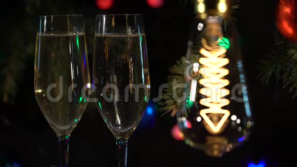 节日气氛花环两杯香槟放在桌子上是亮着的灯泡视频的预览图