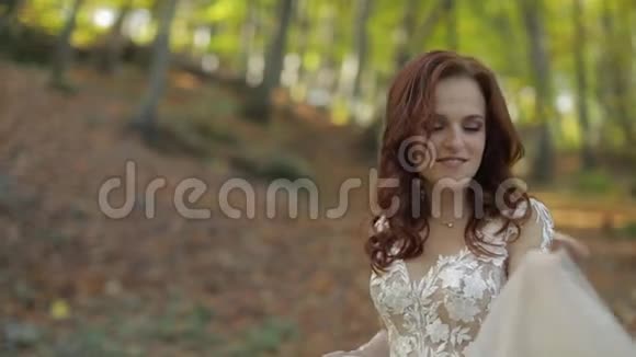 新娘穿着婚纱在森林公园散步很开心恋爱中的女人视频的预览图